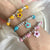 B149 Bracciale cordino cerato con granelli nuovi e fiore di ciliegio smaltato