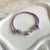 B0277 Bracciale in cordino cerato con granelli e fiore “grazie maestra” passante