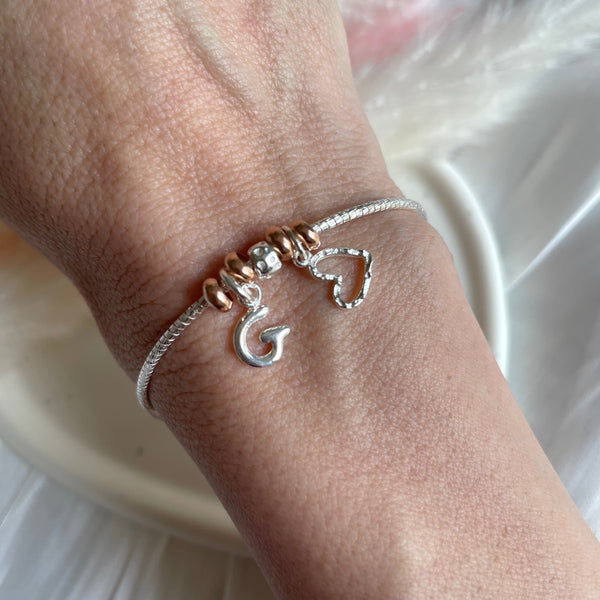 B0269 Bracciale semi rigido con rondelle rosate, granello, cuore e iniziali pendenti