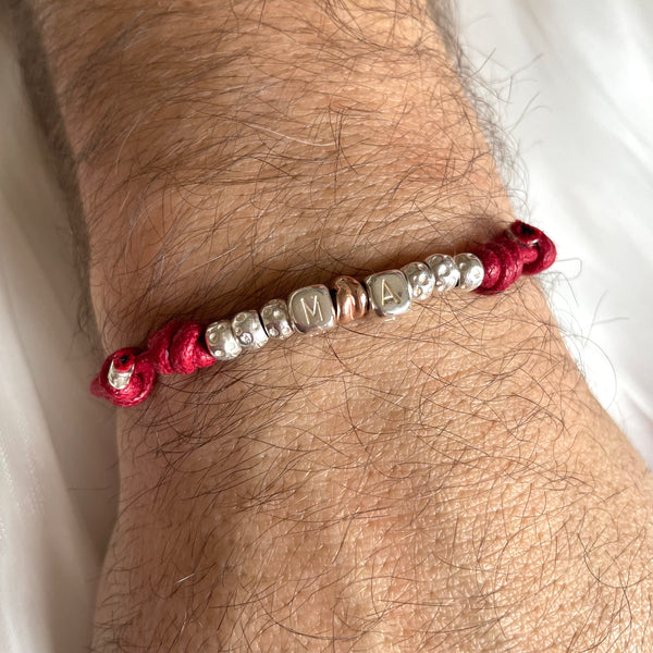 B142 Bracciale con cordino cerato, granelli nuovi, iniziali passanti e intreccino simbolo di unione