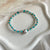 B0280 Bracciale con nodi, palline e fiore passante “grazie maestra”