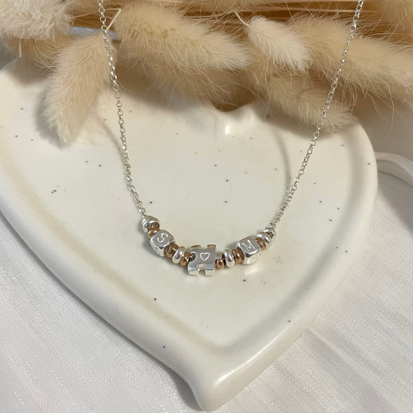CL0159 Collana rolò in argento con rondelle, iniziali cubo e puzzle passante